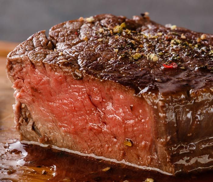 Juicy medium-rare steak with a browned crust, close-up on a plate