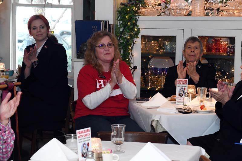 People applauding at a festive table in a bright restaurant or café