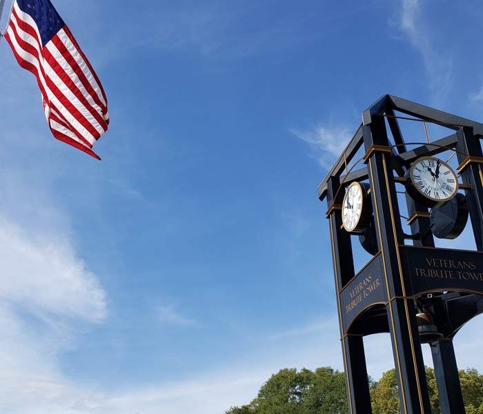 American flag and clock tower against a blue sky