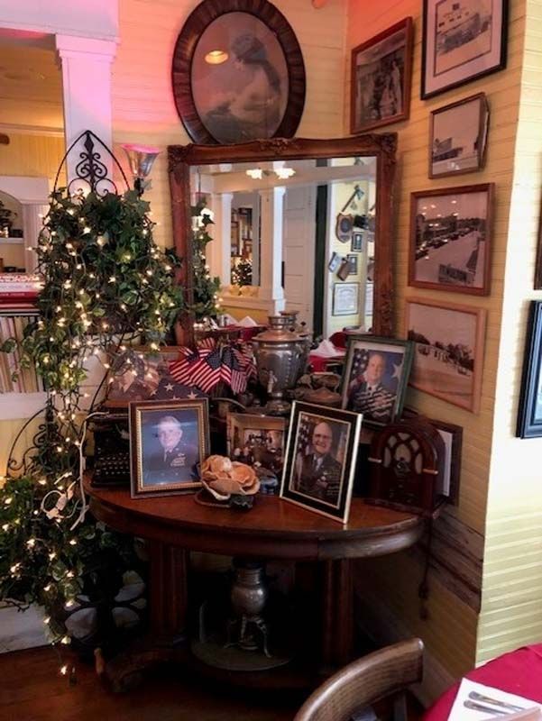 Decorated entryway with Christmas tree, framed photos, and a round table with holiday décor