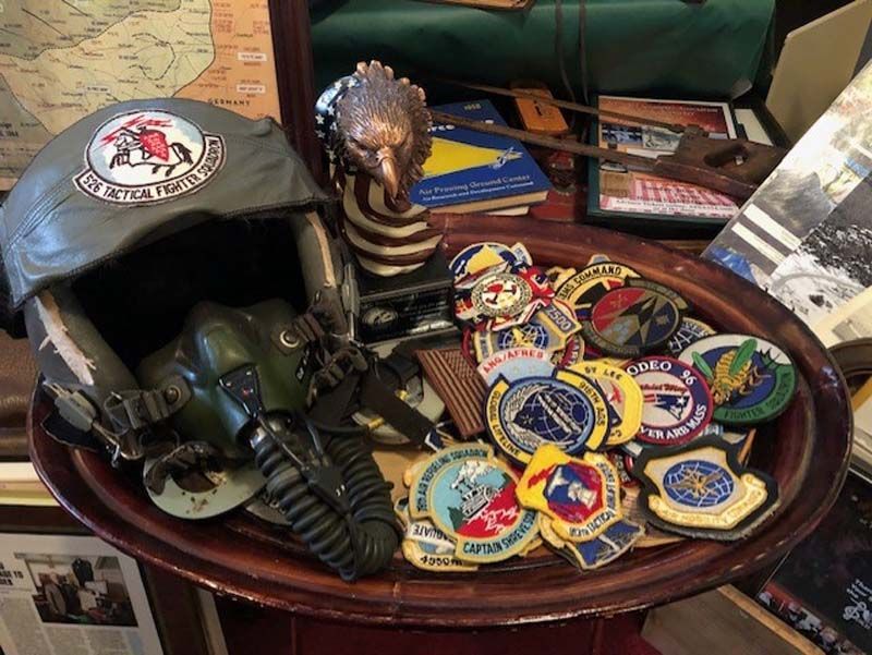Vintage hat, gas mask, and colorful military patches displayed on a wooden table.