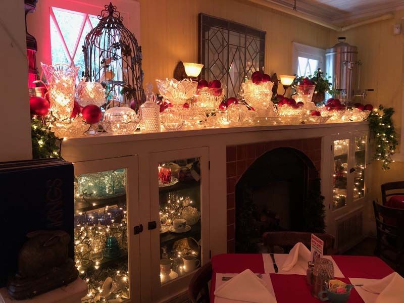 Festive living room mantel with glowing holiday lights, glass decorations, and a decorated fireplace