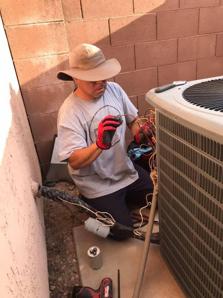 a man wearing a hat and gloves is working on an air conditioner .