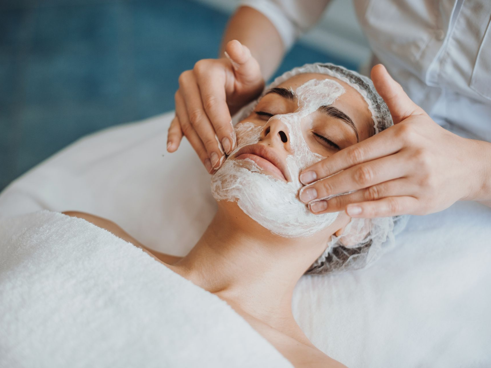 Spa facial treatment with a person receiving a foamy face massage on a treatment bed