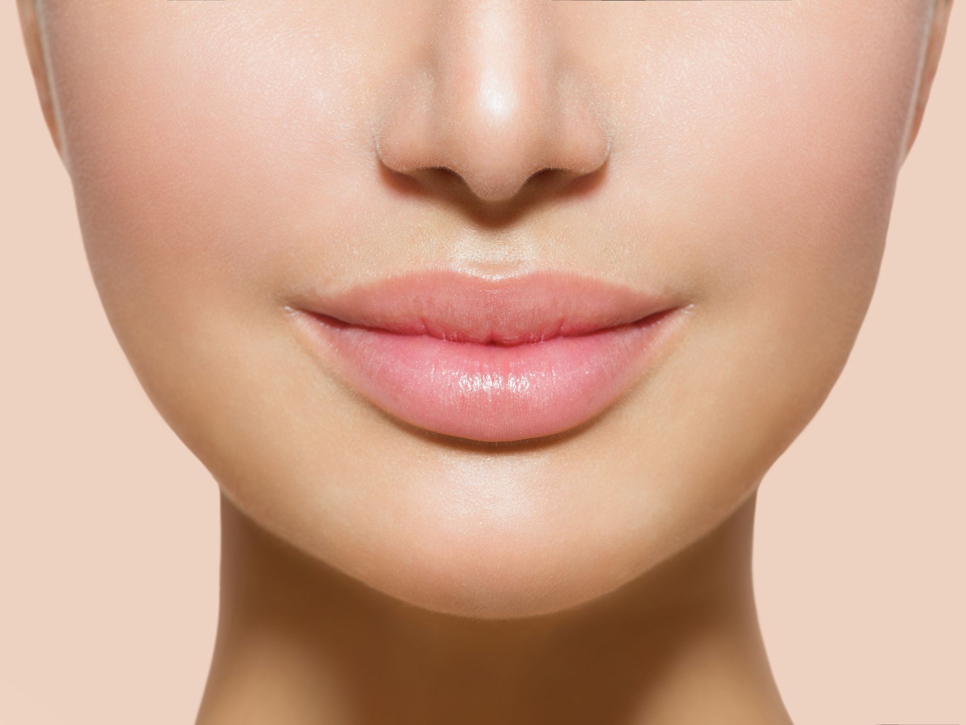 Close-up of a face showing glossy pink lips and smooth skin
