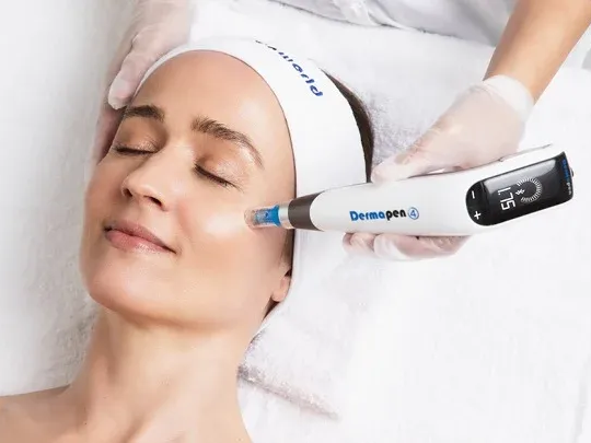 Woman receiving a facial treatment with a handheld device while lying on a white treatment bed