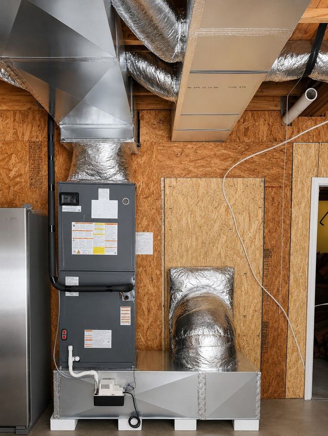 Unfinished basement with insulation, exposed beams, HVAC unit, and ductwork along the wall