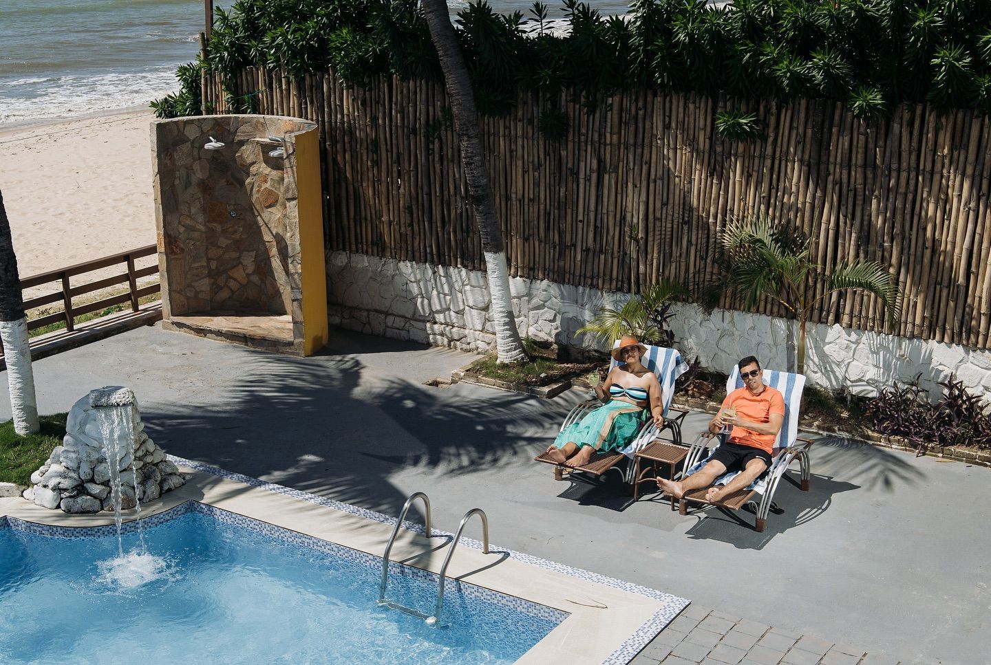 Two people are sitting in chairs near a swimming pool
