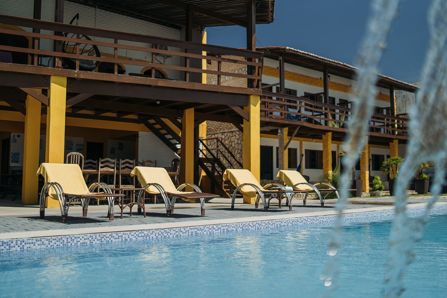 A swimming pool with chairs and a fountain in front of a building
