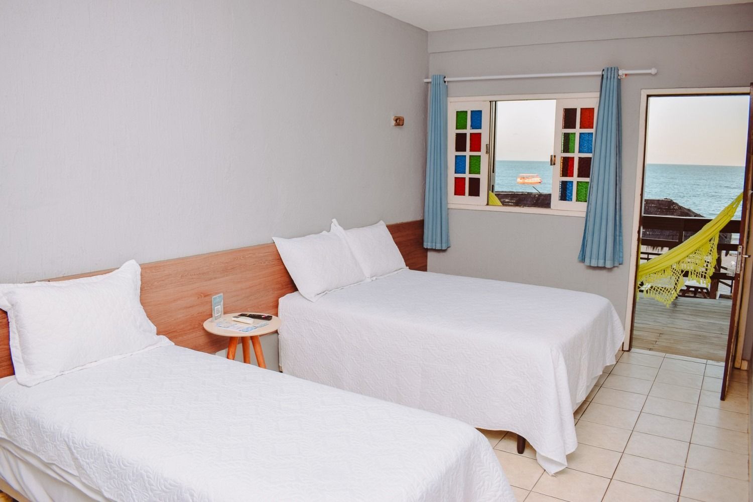 A hotel room with two beds and a window overlooking the ocean.