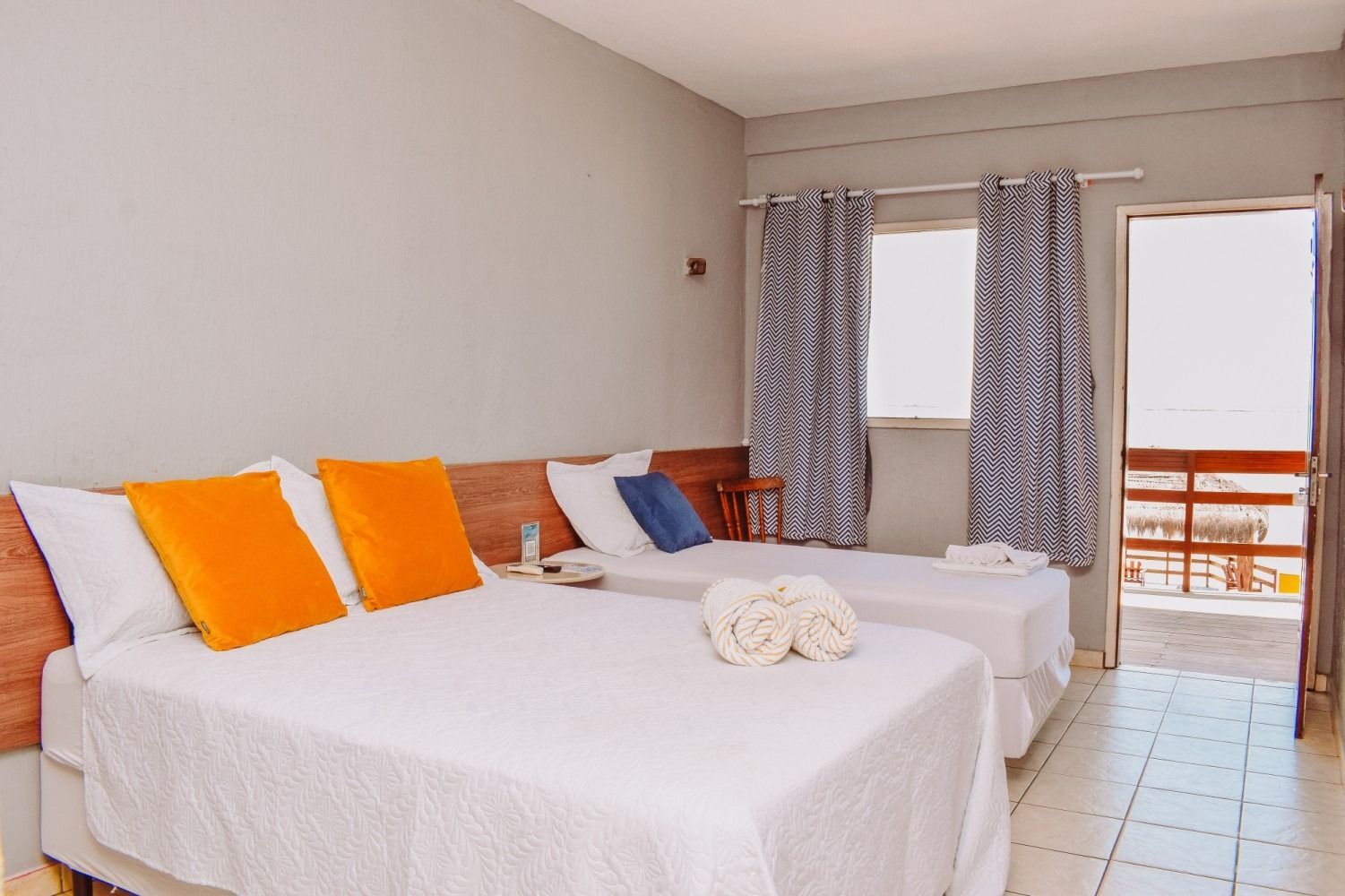 A hotel room with two beds and a balcony.