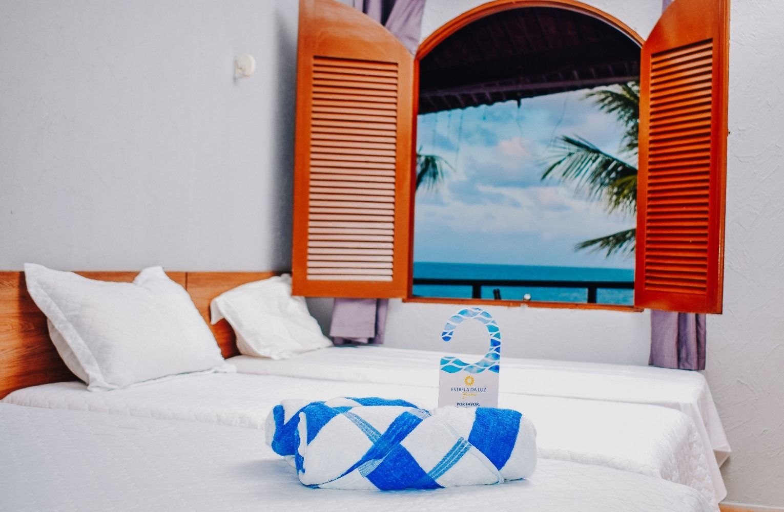 A hotel room with two beds and a window overlooking the ocean.