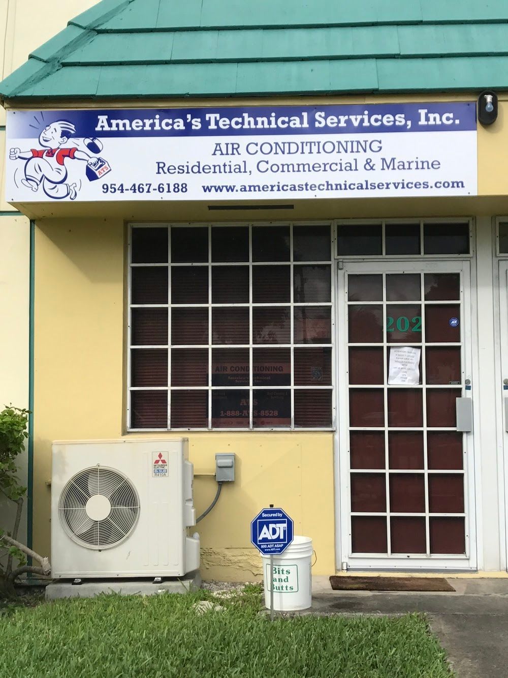 America's Technical Services building with a Mitsubishi AC unit, blue and white sign, and a white door.