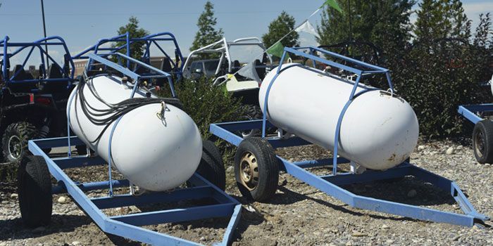 Dos tanques de propano están en un remolque al lado de un buggy.