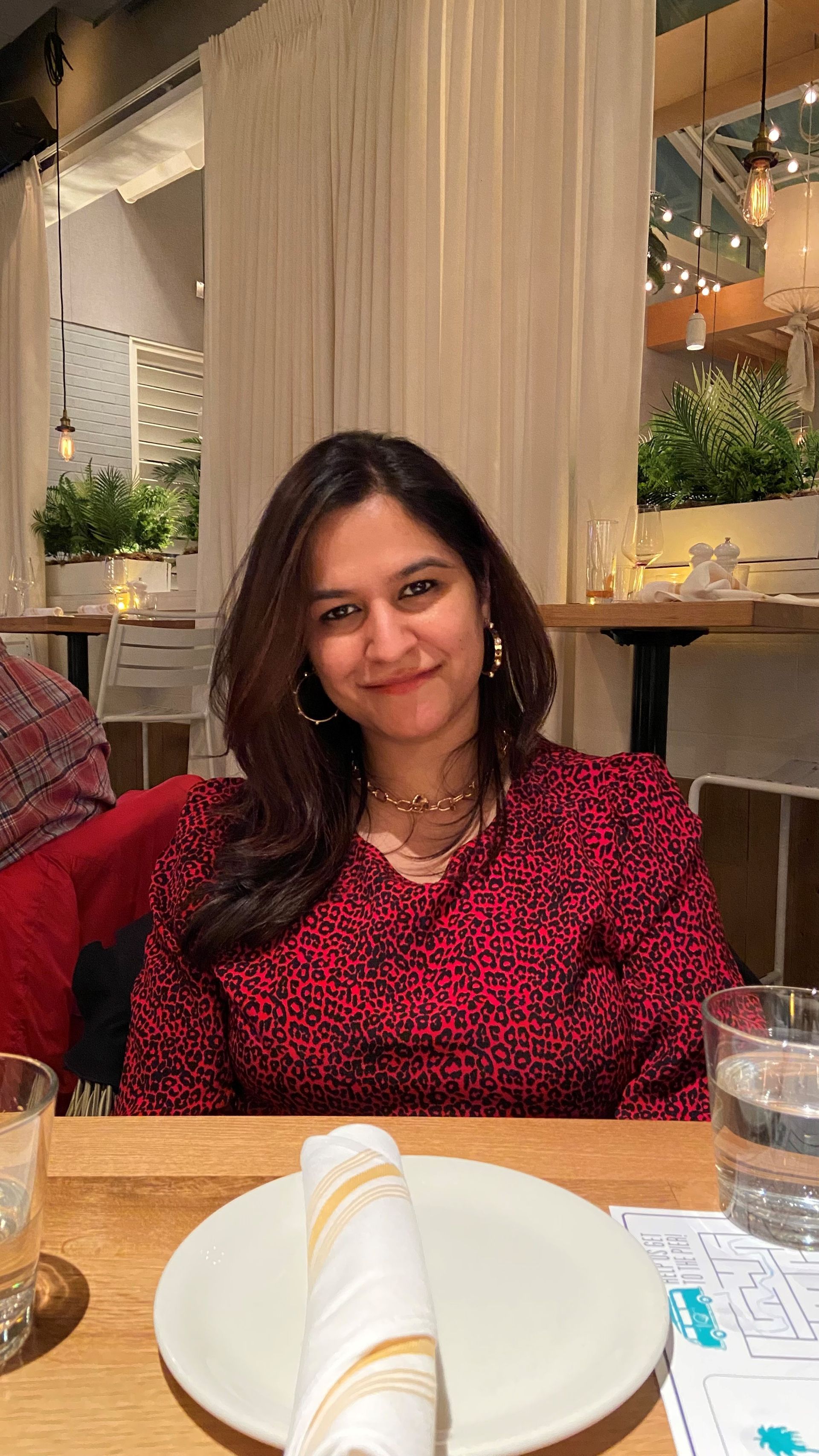 A woman is sitting at a table with a plate of food and a glass of water.