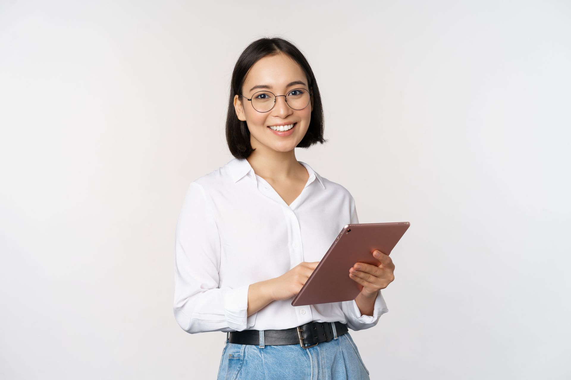 A woman wearing glasses is holding a tablet and smiling.