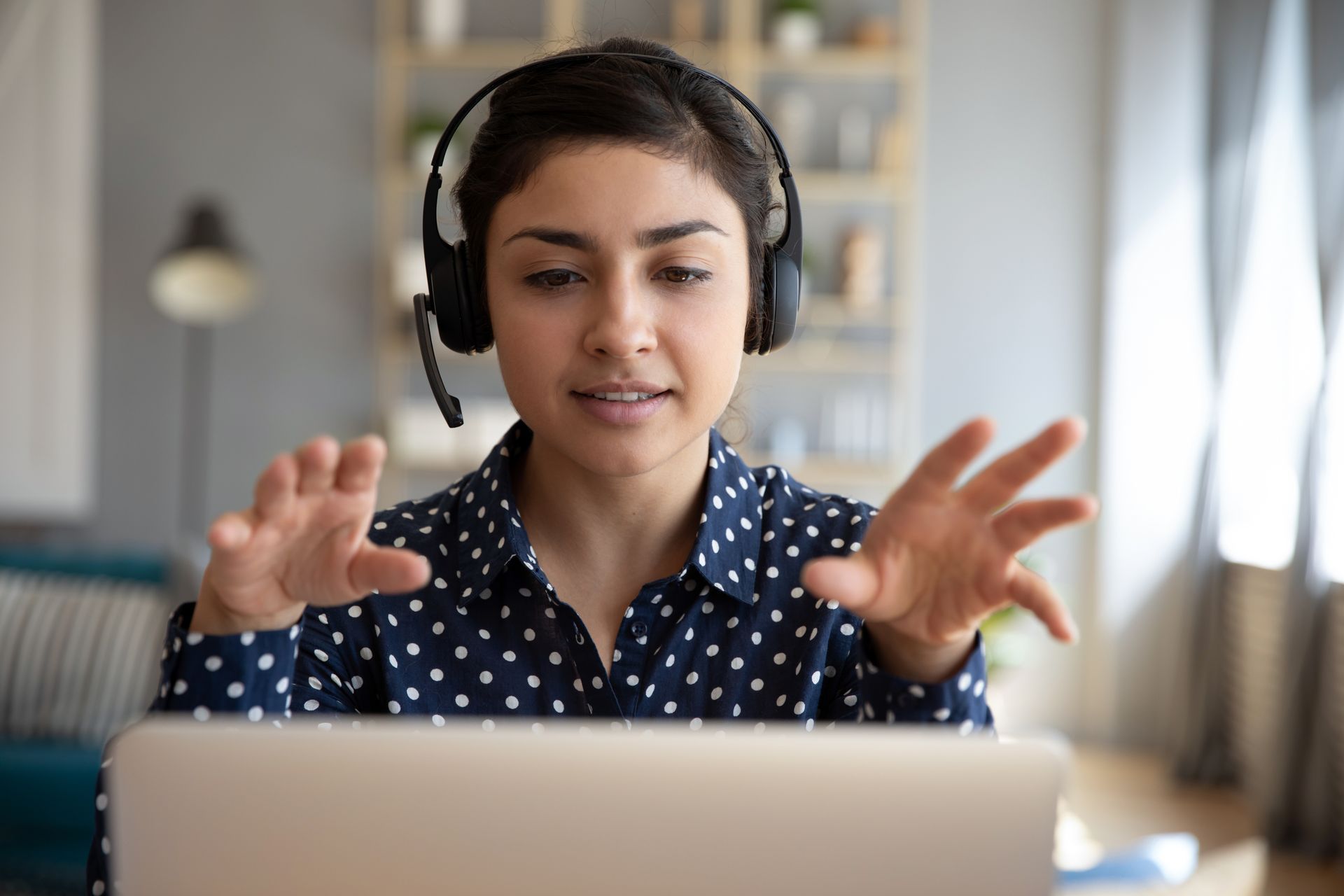 A woman wearing headphones is sitting in front of a laptop computer.