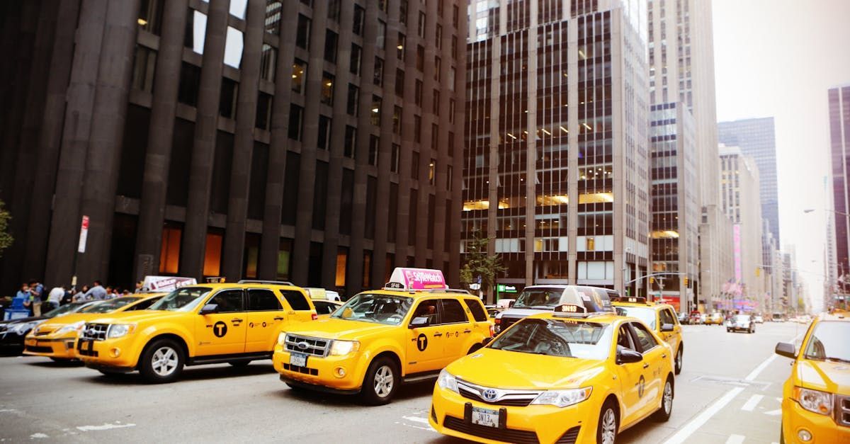 A row of yellow taxis are driving down a city street.