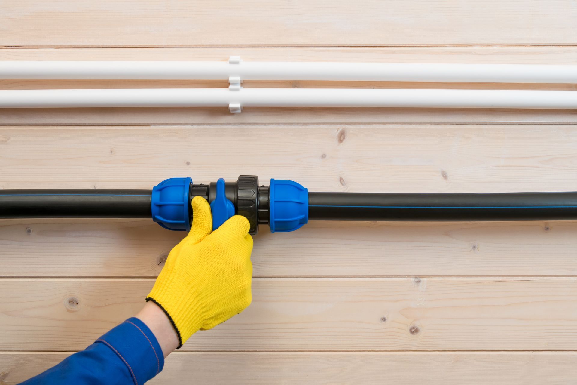 A person wearing a yellow glove is connecting two pipes.
