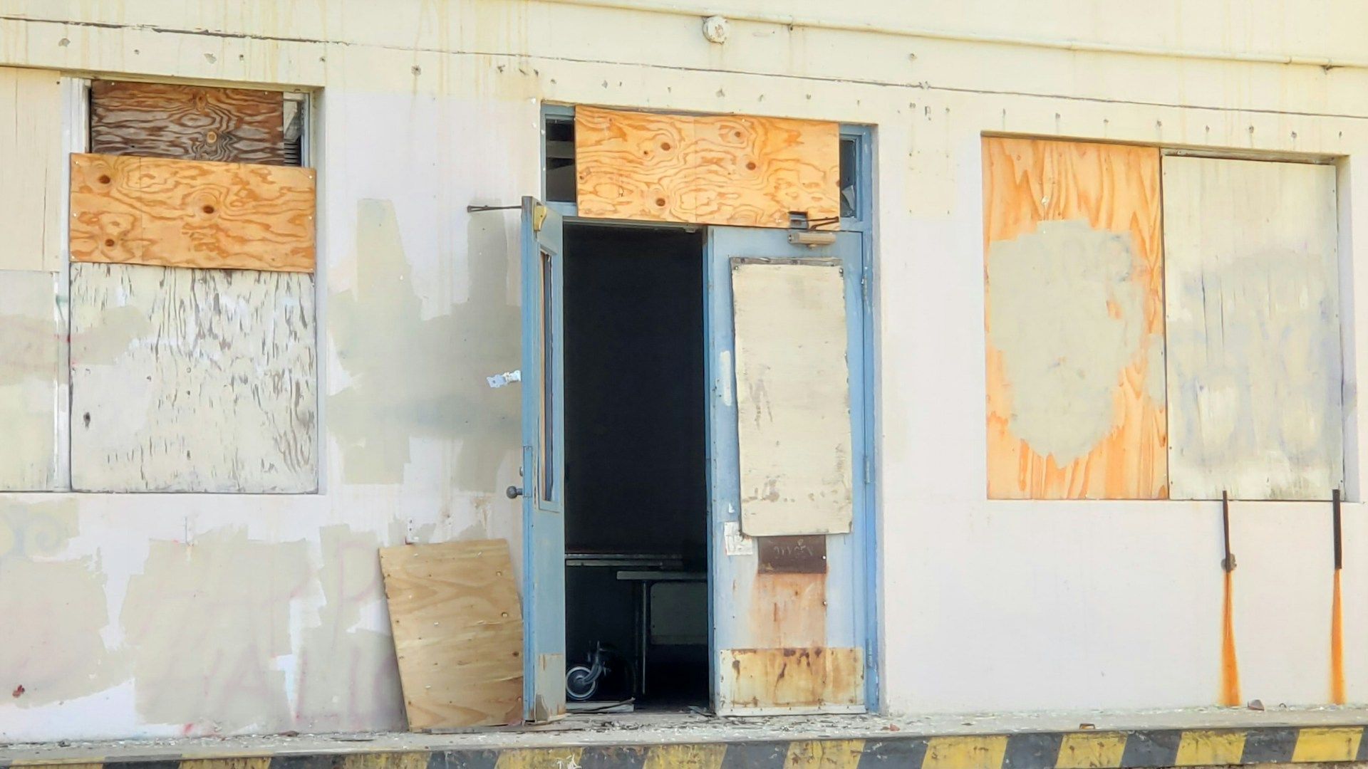 Emergency Board-Ups An old building with a door and windows boarded up.