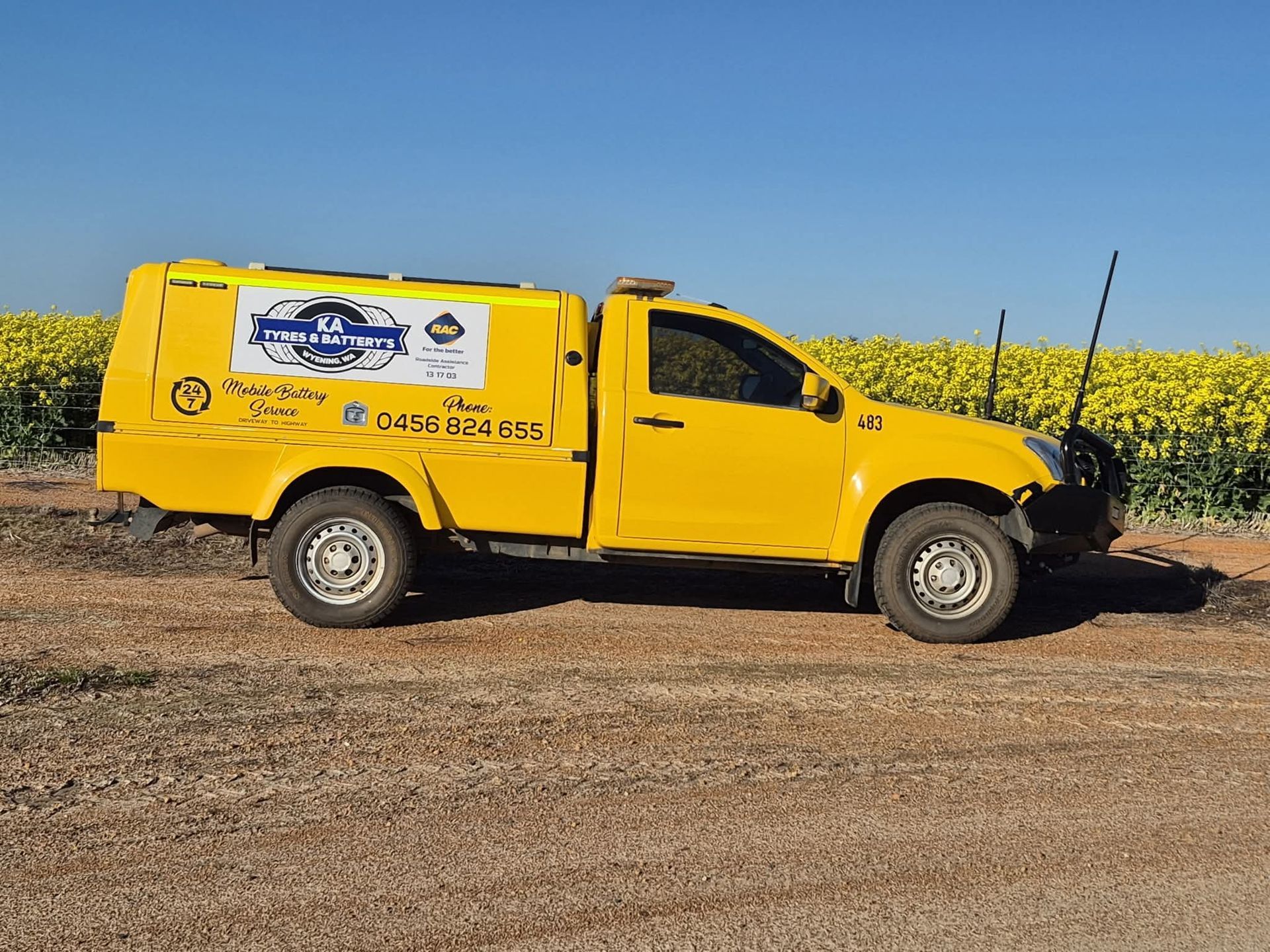 Two utility trucks parked side by side outside a worksite building and flags.
