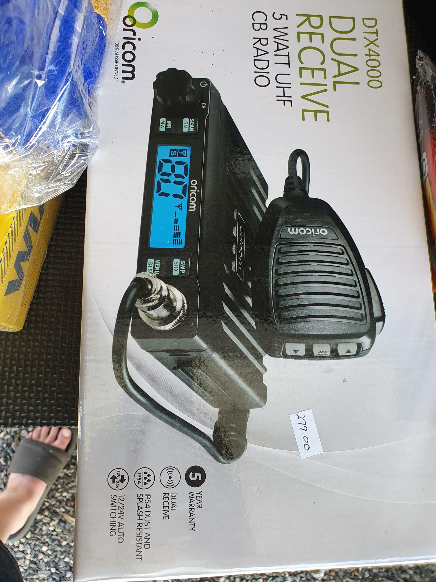 Boxed Orion CB radio set with handheld microphone and antennas, shown on a product package.
