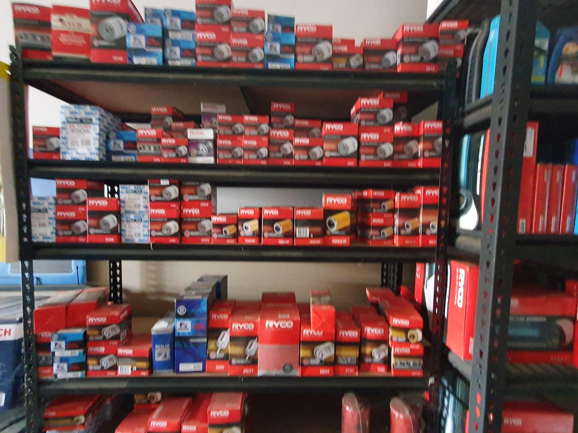 Shelves stocked with red and black boxes of automotive parts in a warehouse aisle