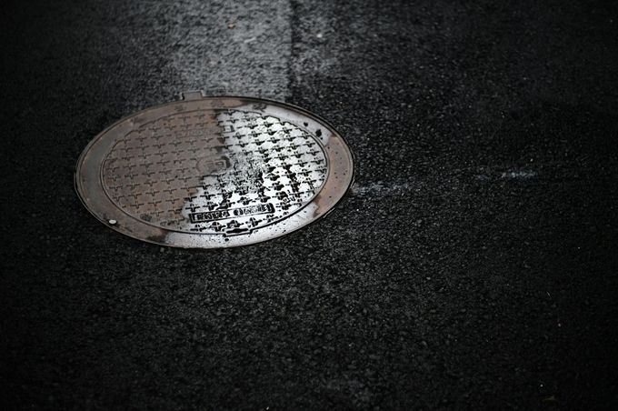 Round metal manhole cover on dark asphalt pavement