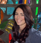 Smiling woman with long dark hair in front of a colorful mosaic wall