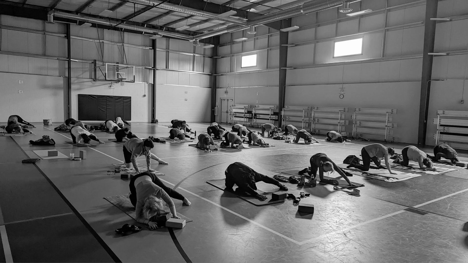 People stretching on mats in a large indoor gym or warehouse space