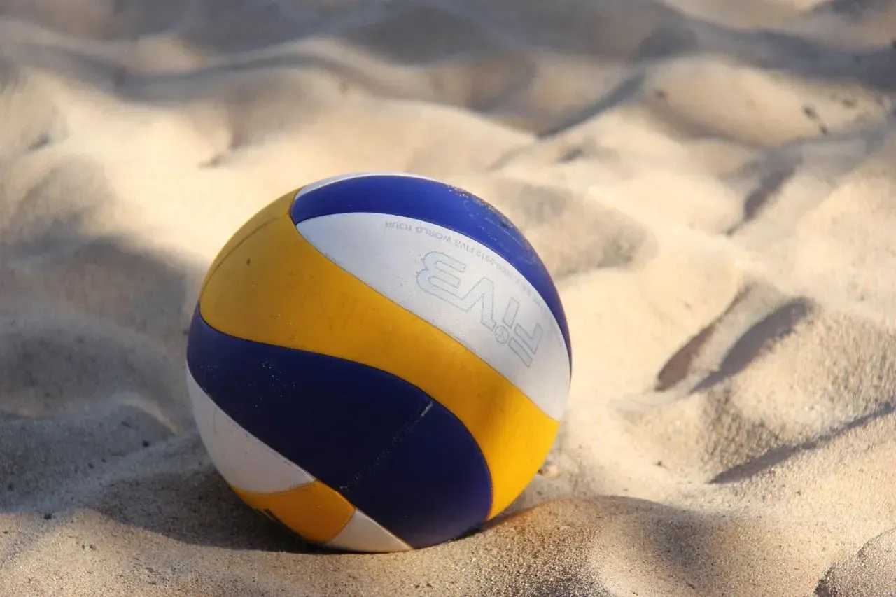 Volleyball on sand, featuring blue, yellow, and white panels. Volleyball on sand, featuring blue, yellow, and white panels.