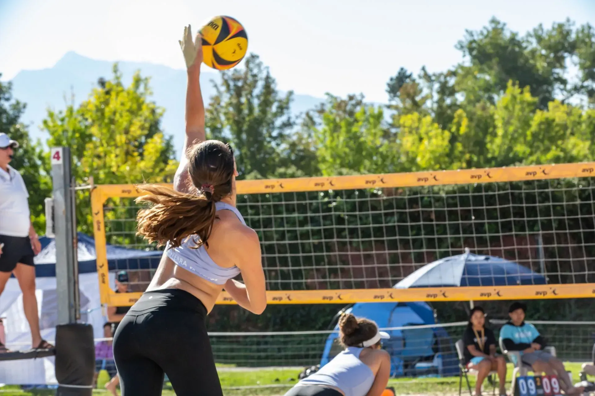 Woman spiking a volleyball on a beach court. 