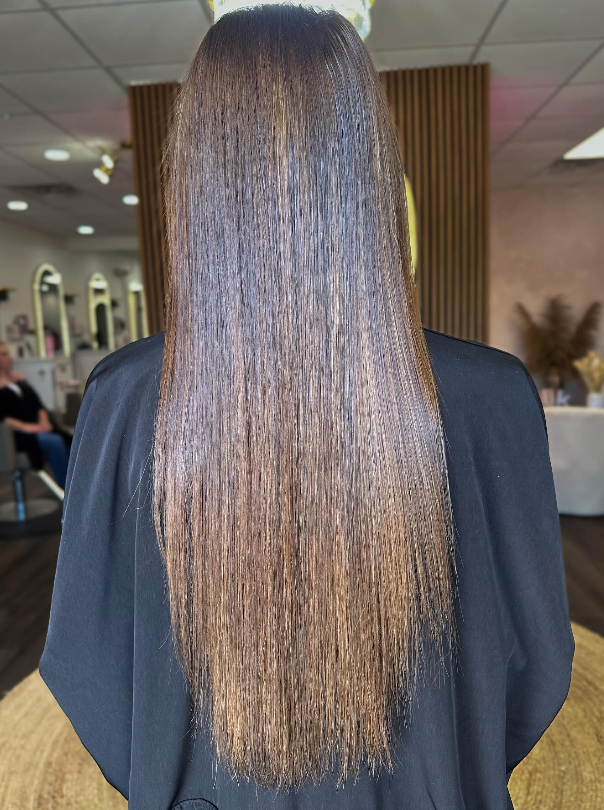 Person with long straight brown hair seen from behind in an indoor salon setting