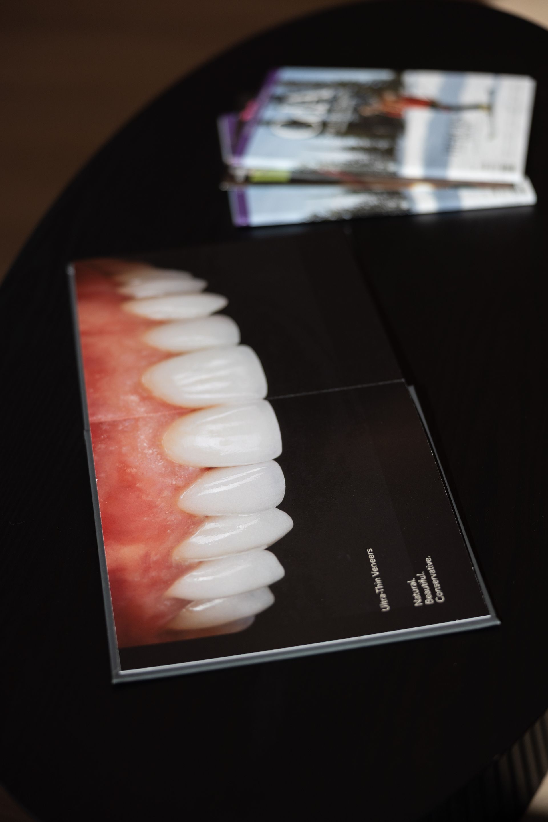 Dental shade guide beside a close-up smile photo on a black surface