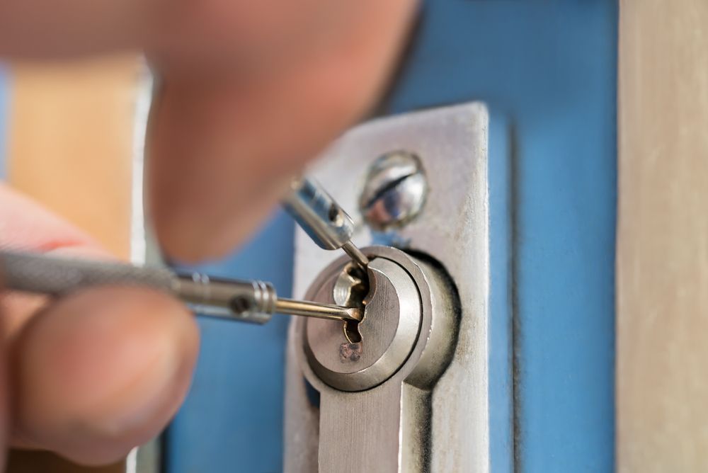 Hands Picking a Door Lock With Two Metal Lock Picks — Lake Macquarie Mobile Locksmiths in Warners Bay, NSW