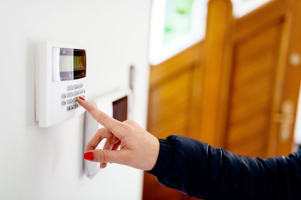 Person's Hand With Red Nail Polish Entering a Code Into a Security Alarm