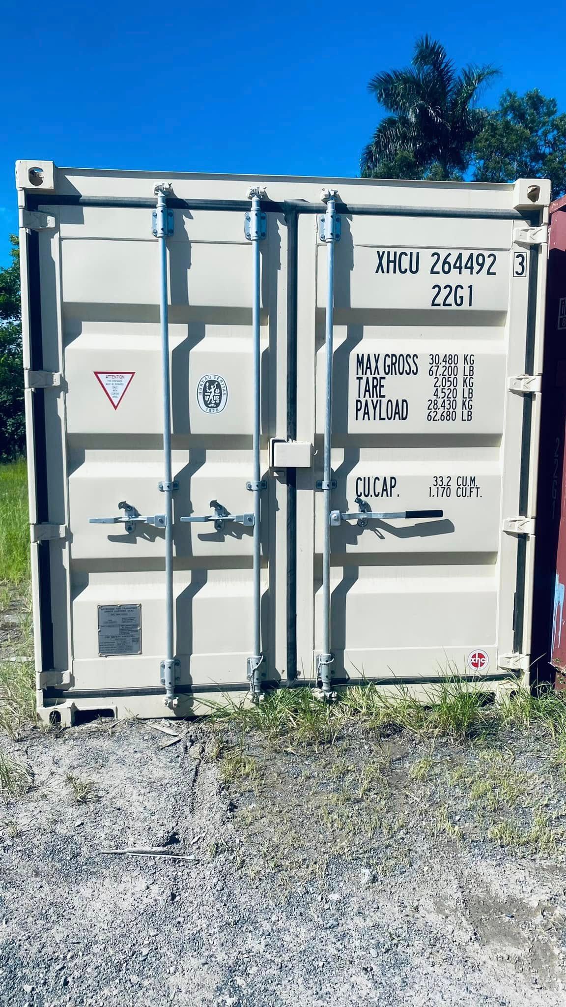 Tan Shipping Container With Closed Doors on Gravel Against a Blue Sky — Johnny Farming Company In Ooralea, QLD