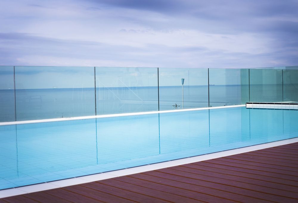 Rooftop Pool With Glass Barriers Overlooking a Calm Ocean Under a Cloudy Sky — Gympie Fence Inspections in Glenwood, QLD