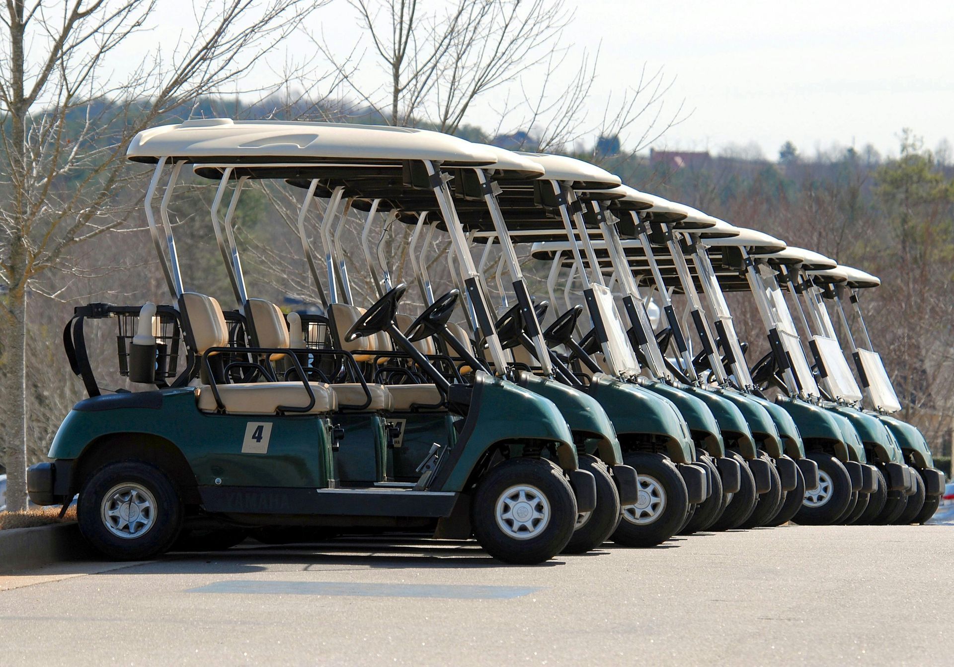 A row of golf carts parked in a parking lot.