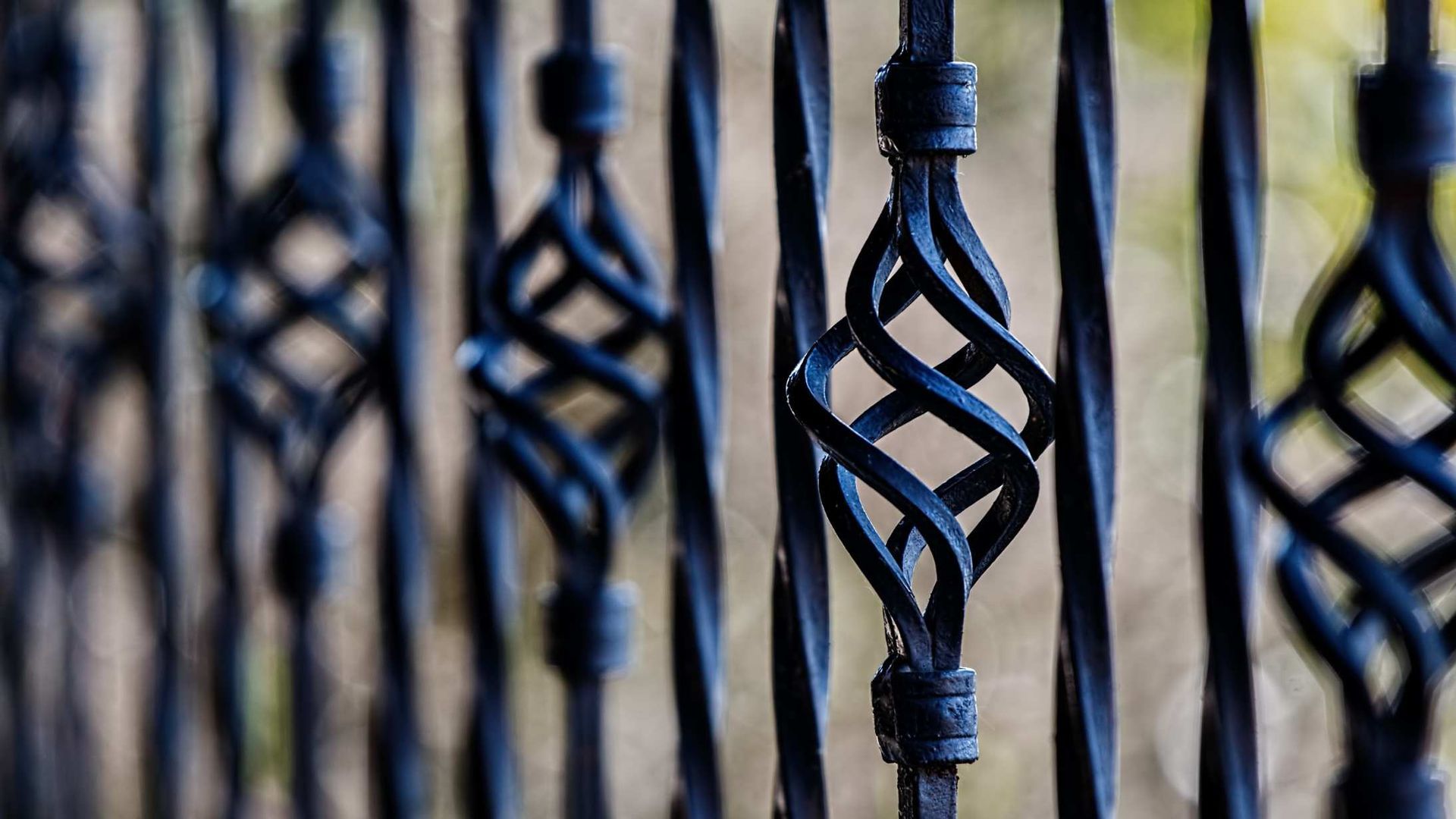 Black metal fence with decorative twisted vertical bars, viewed close-up.