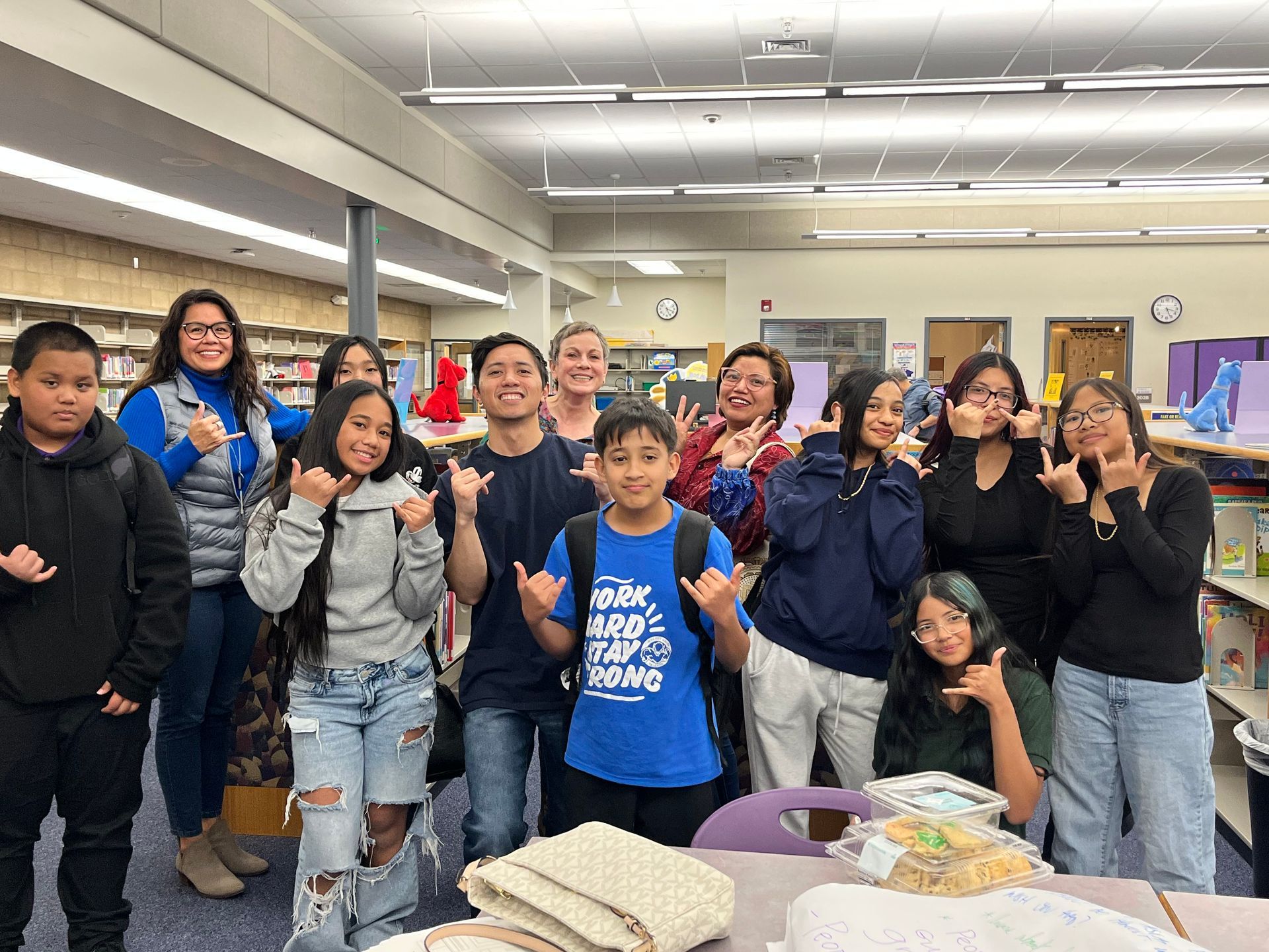 Group of students posing and smiling in a classroom beside a table with food and drinks