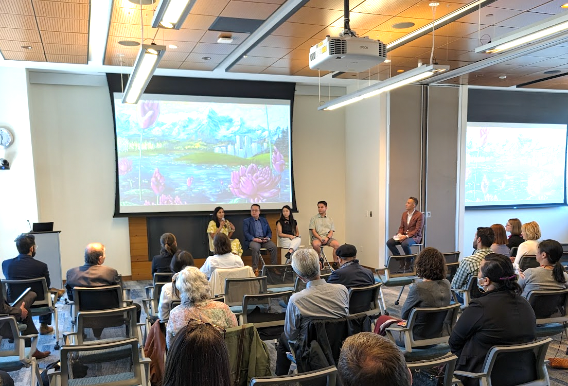 Conference talk in a bright room, with audience seated facing a large presentation screen.