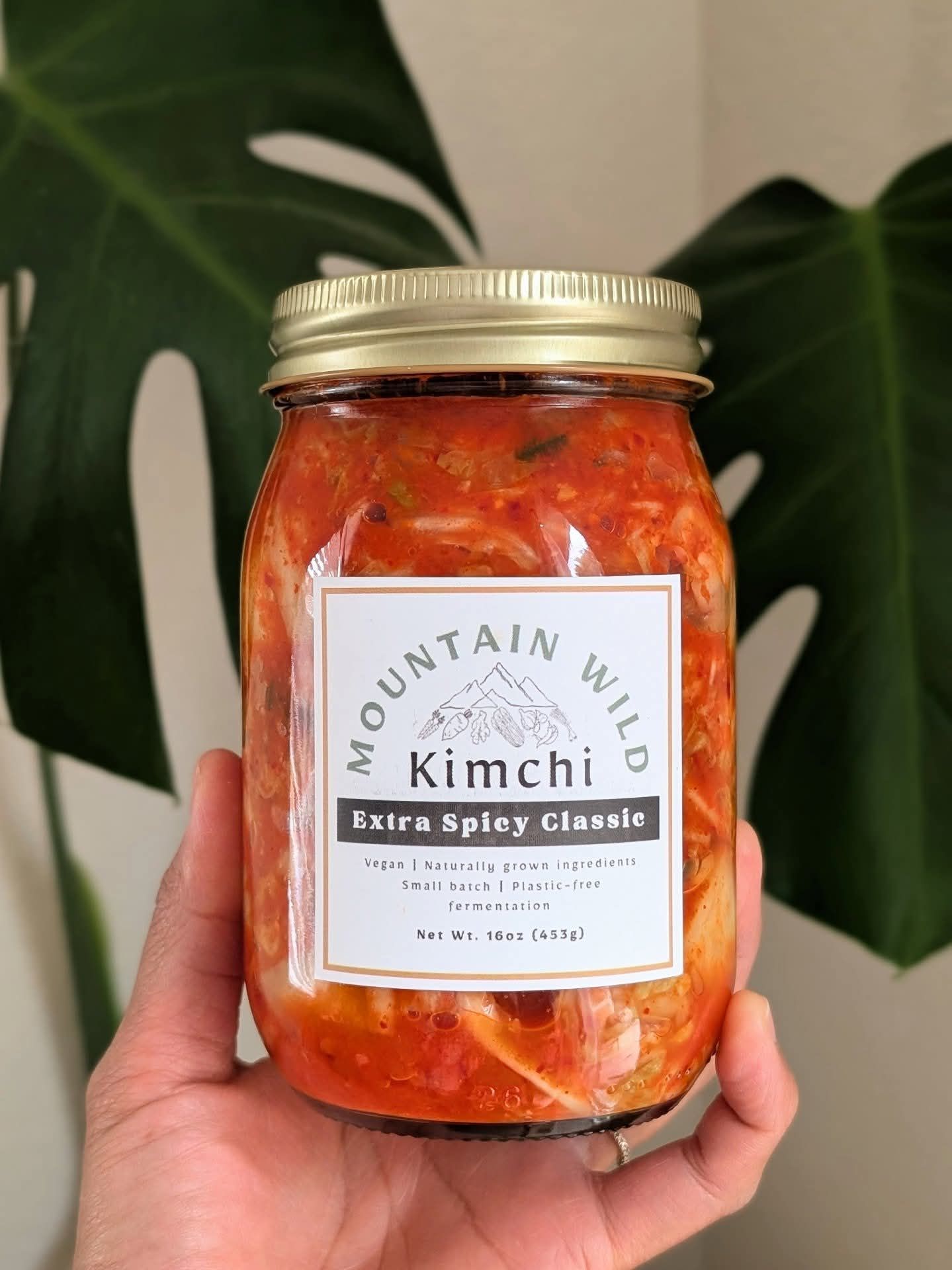 Hand holding jar of Mountain Wild kimchi, 