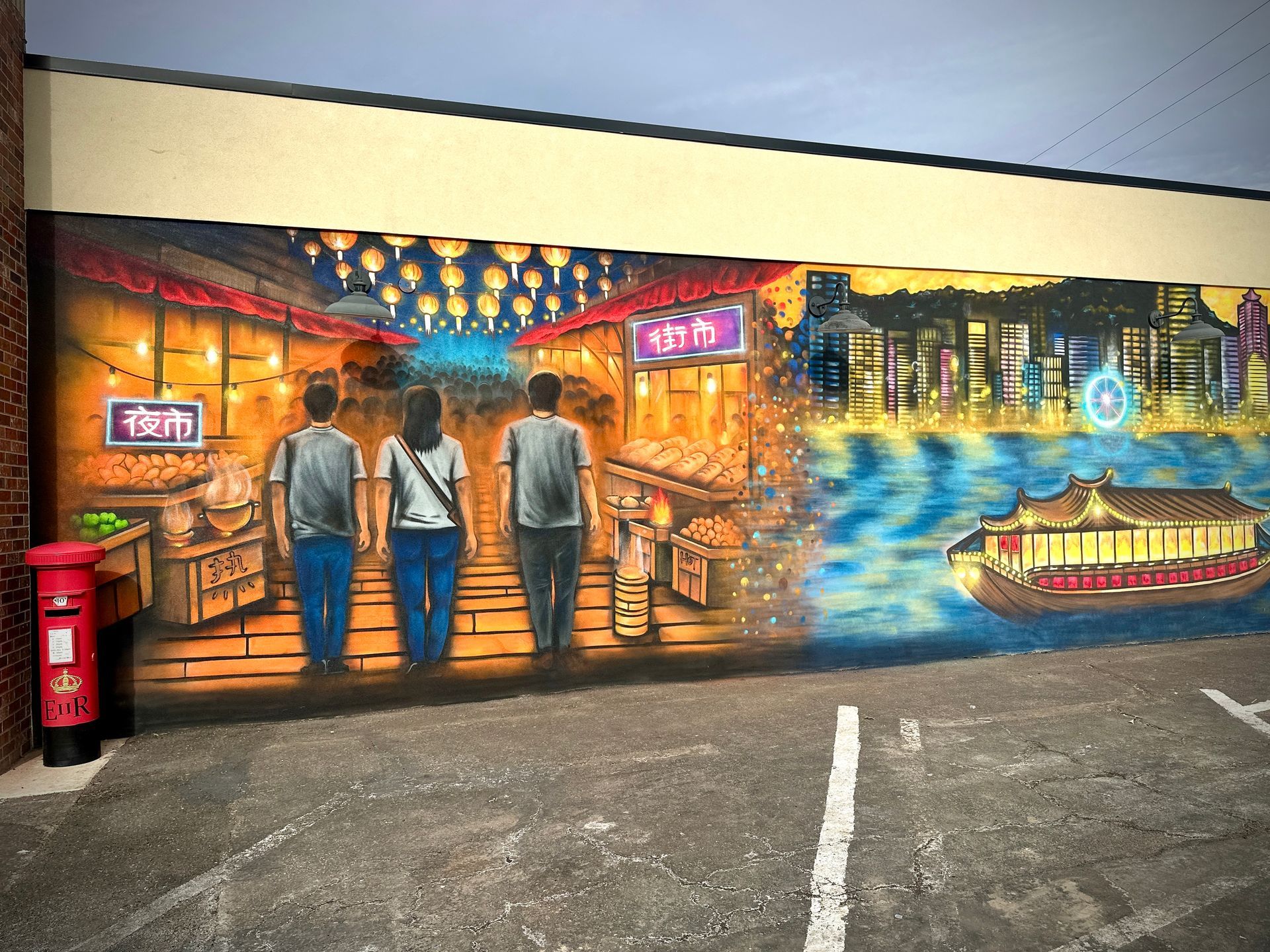 Mural of three people walking through a night market toward a cityscape with a boat on water.