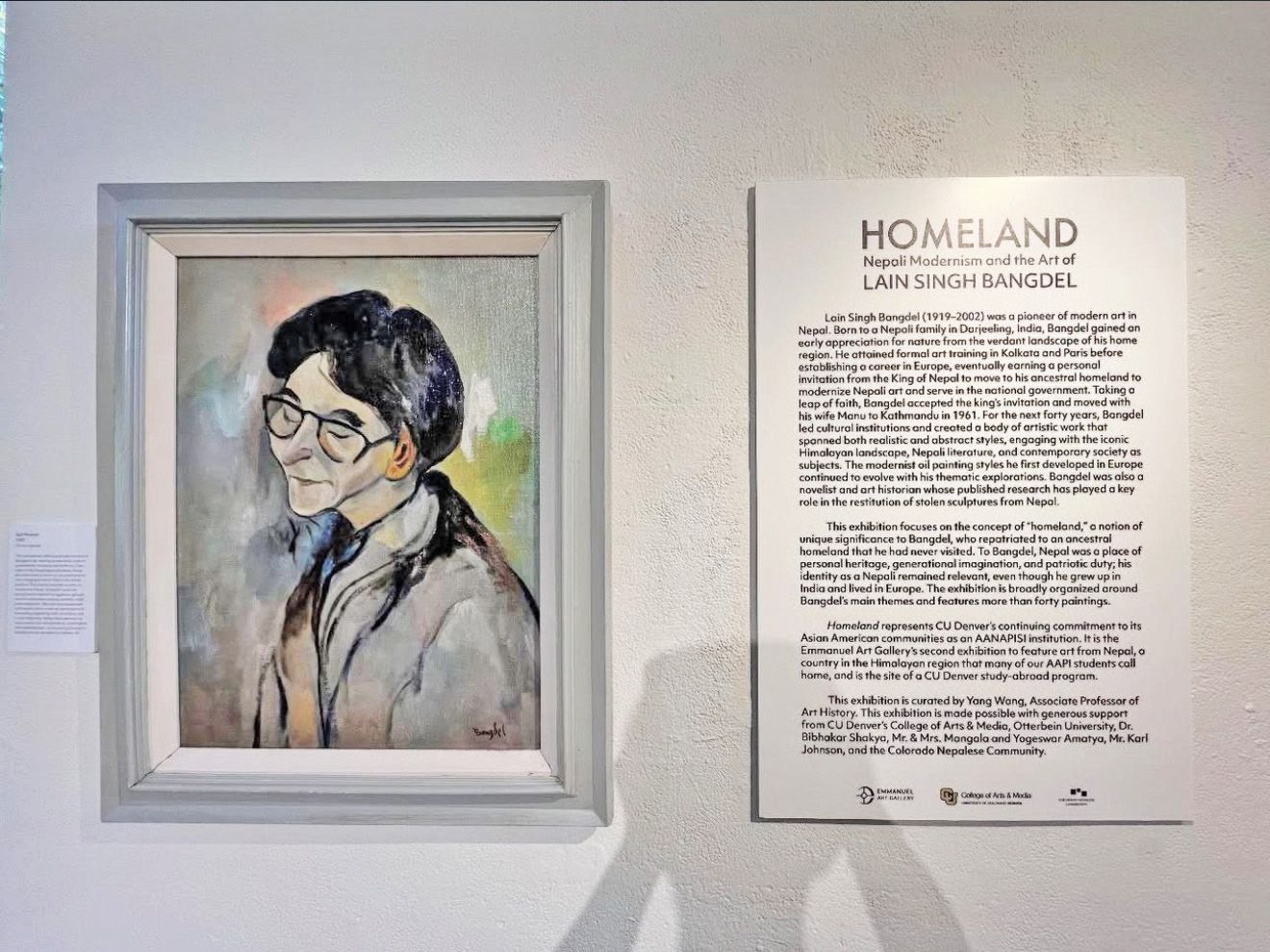 A framed portrait of a person with glasses next to a sign with text.