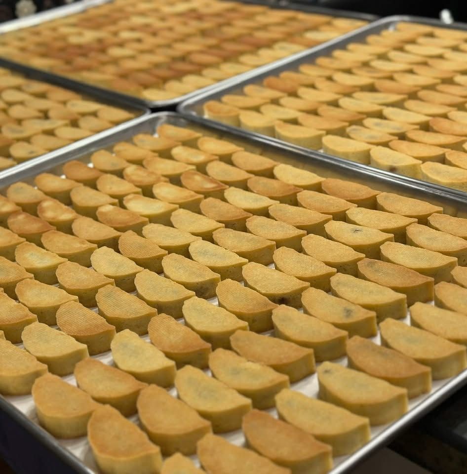 Rows of golden, semi-circular pastries on baking sheets, ready to serve.