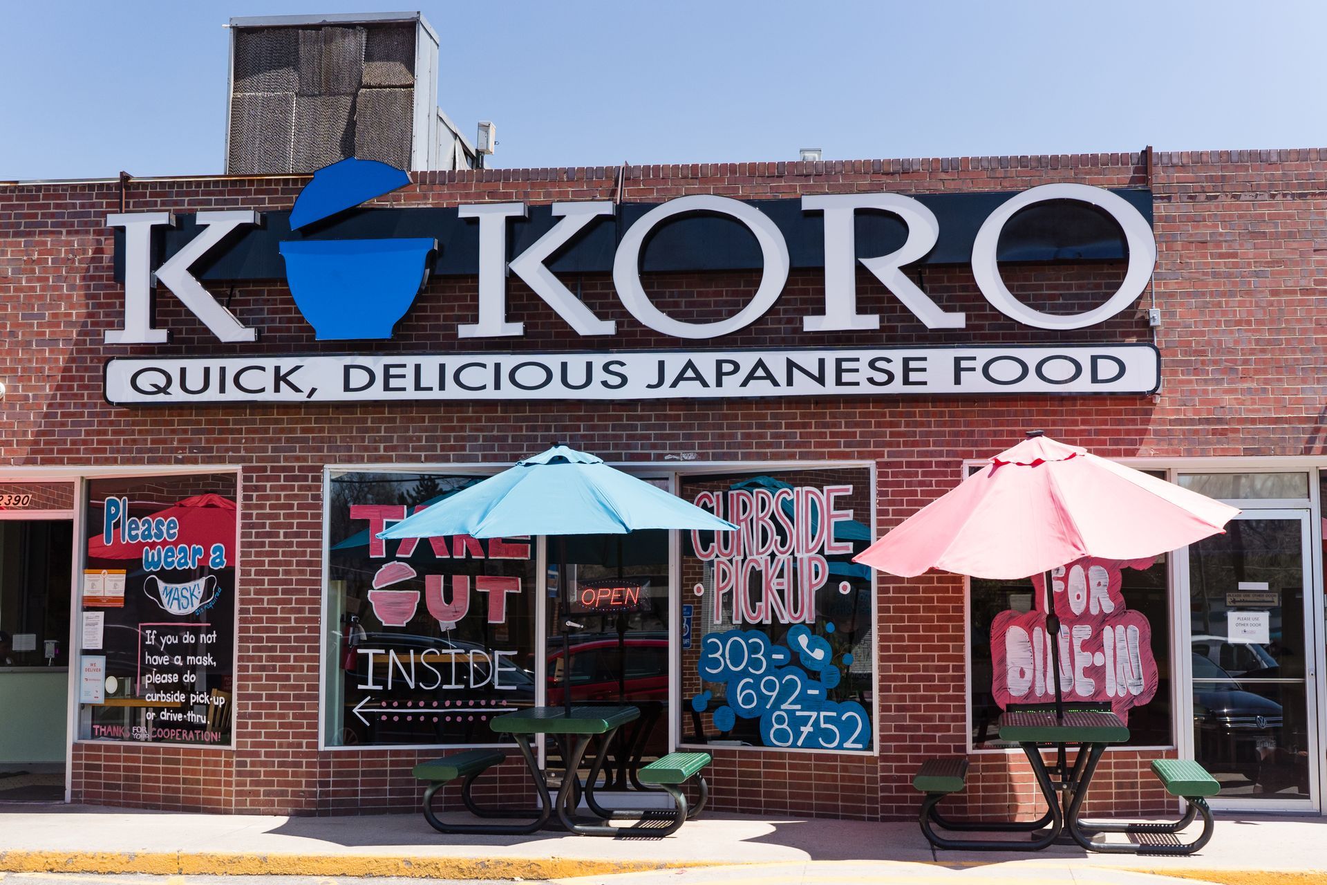 Storefront sign for KOKORO Japanese food with patio tables, umbrellas, and bright window posters