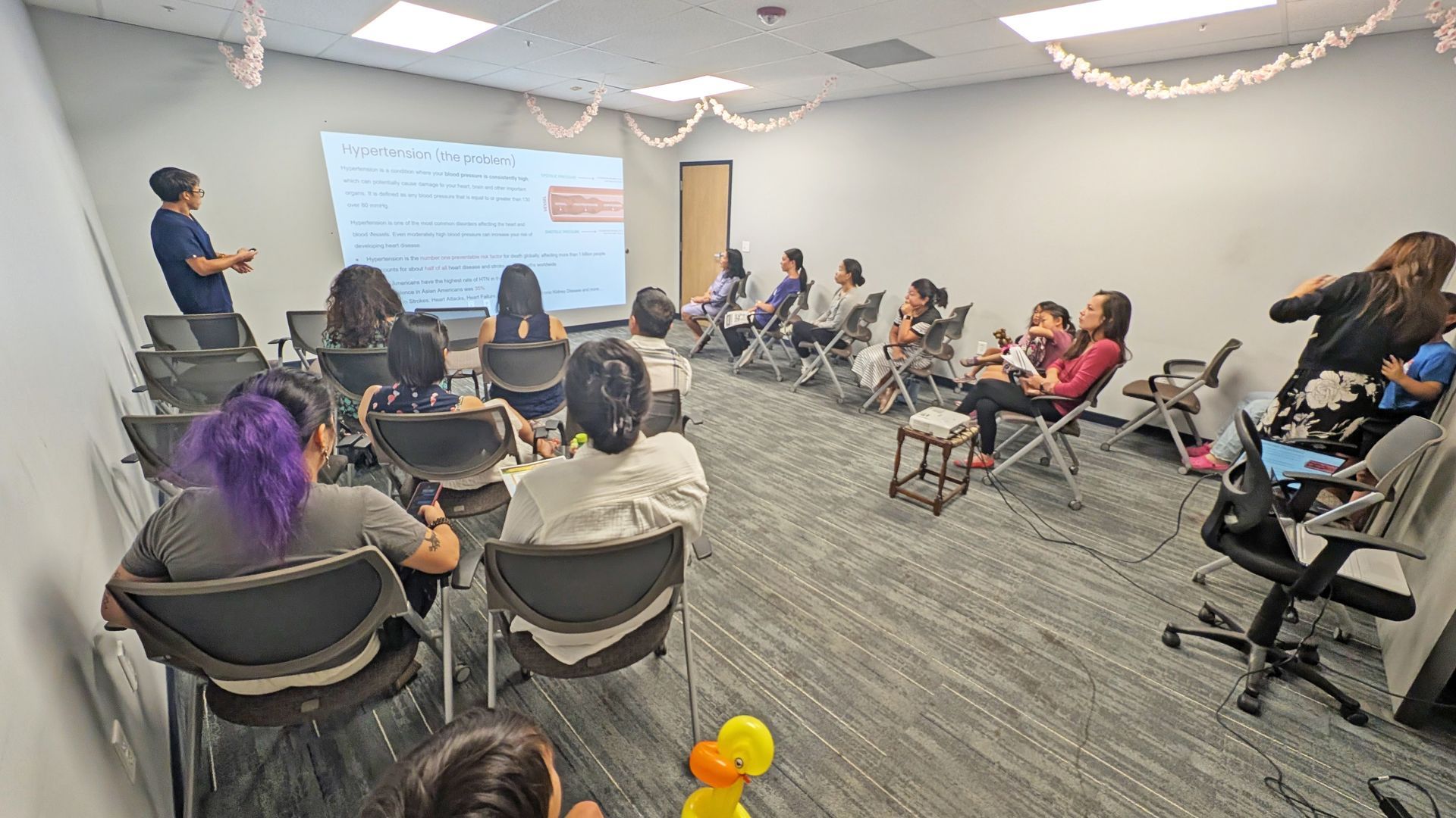 People in a classroom setting watching a presentation on a screen.
