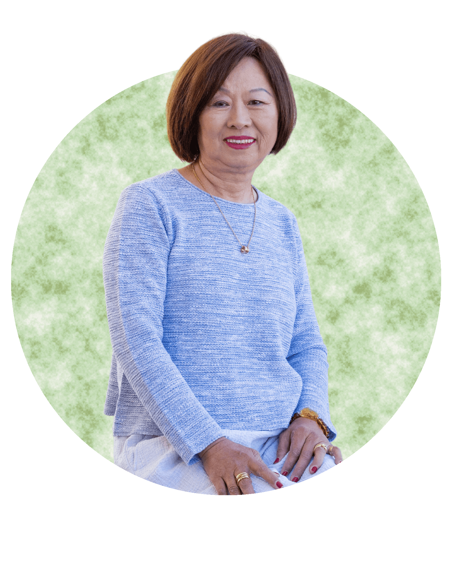 Woman in a light blue sweater, seated and smiling against a soft green circular backdrop.