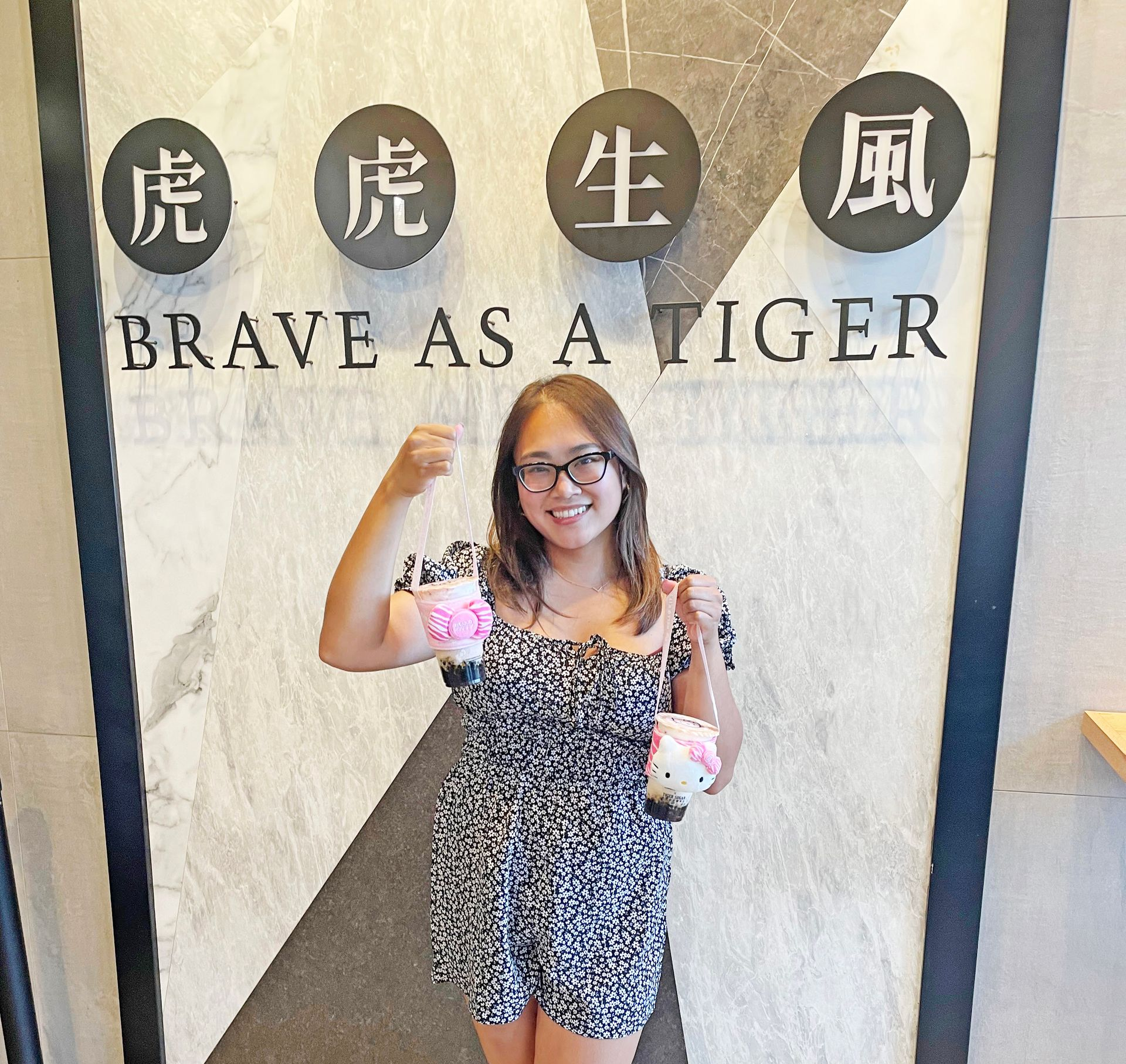 Woman holding drinks, smiling, in front of a